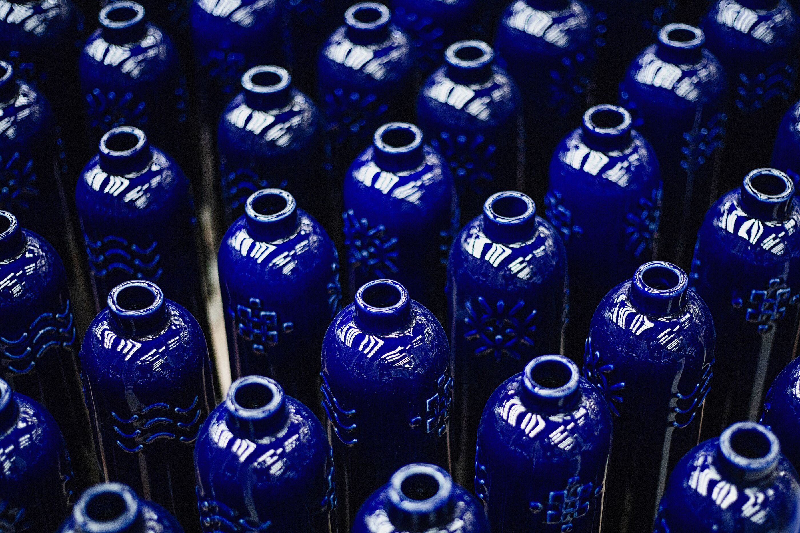 Rows of cobalt blue ceramic Komos bottles, glazed, in production